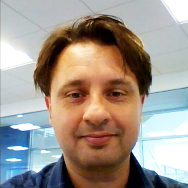 A smiling middle-aged man. He has medium-length, dark hair.