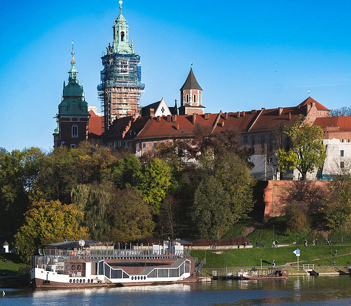 View of a restaurant barge on the river. Medieval castle in the background.