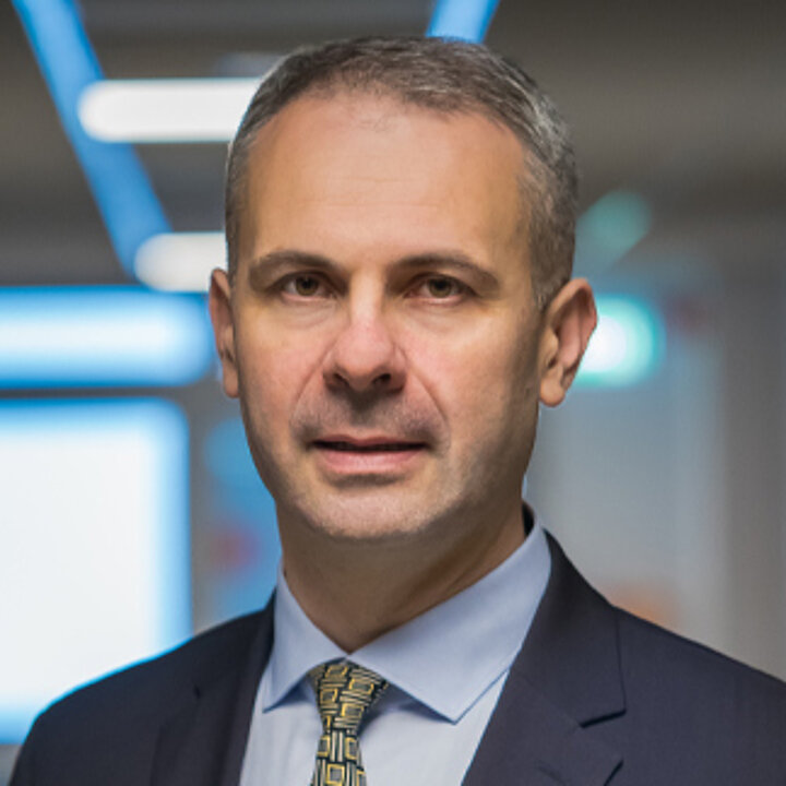 A middle-aged man in a blue jacket and light blue shirt.